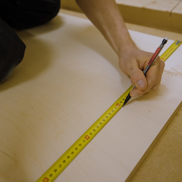 person measuring wooden furniture