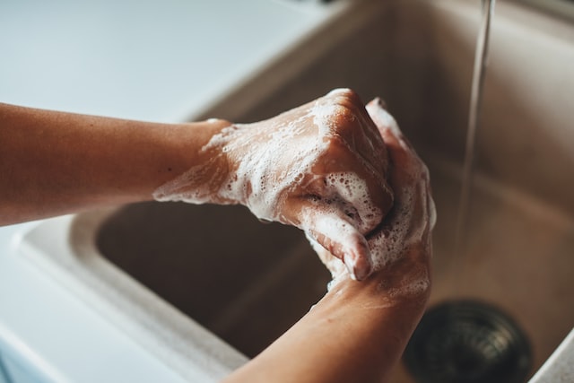 person washing hands above kitchen sink