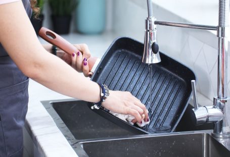 person washing the grill under the stainless faucet