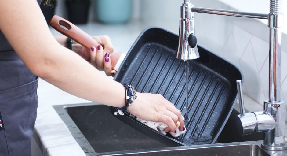 person washing the grill under the stainless faucet