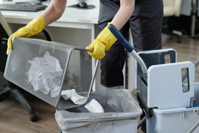 person putting trash in garbage can